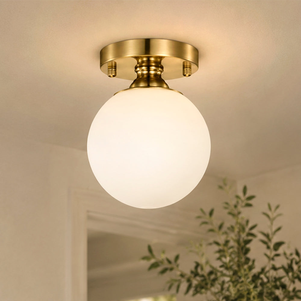 Brass glass globe flush mount ceiling light in a warm hallway